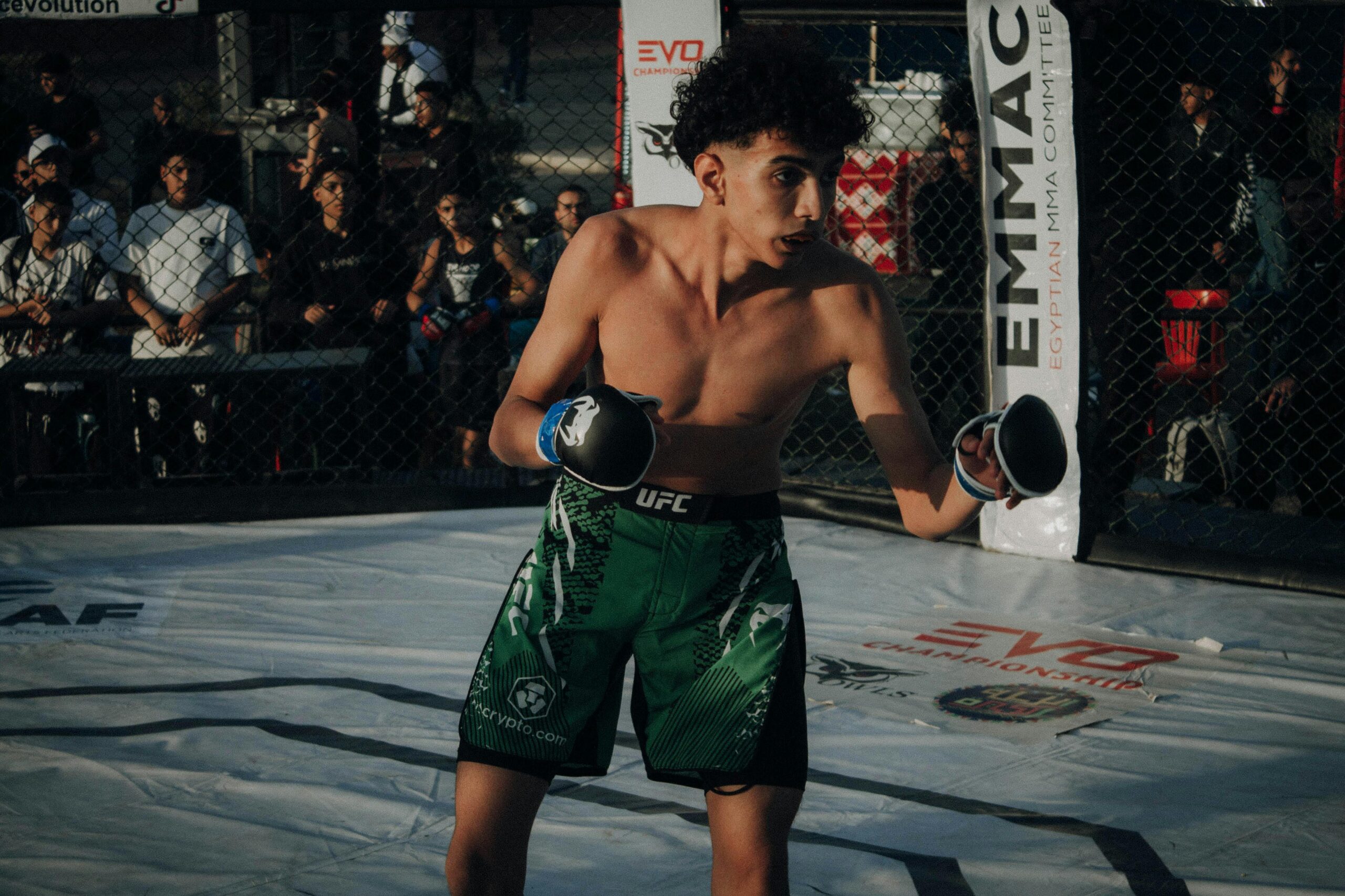 Home Young male fighter in action during an MMA fight in a cage.
